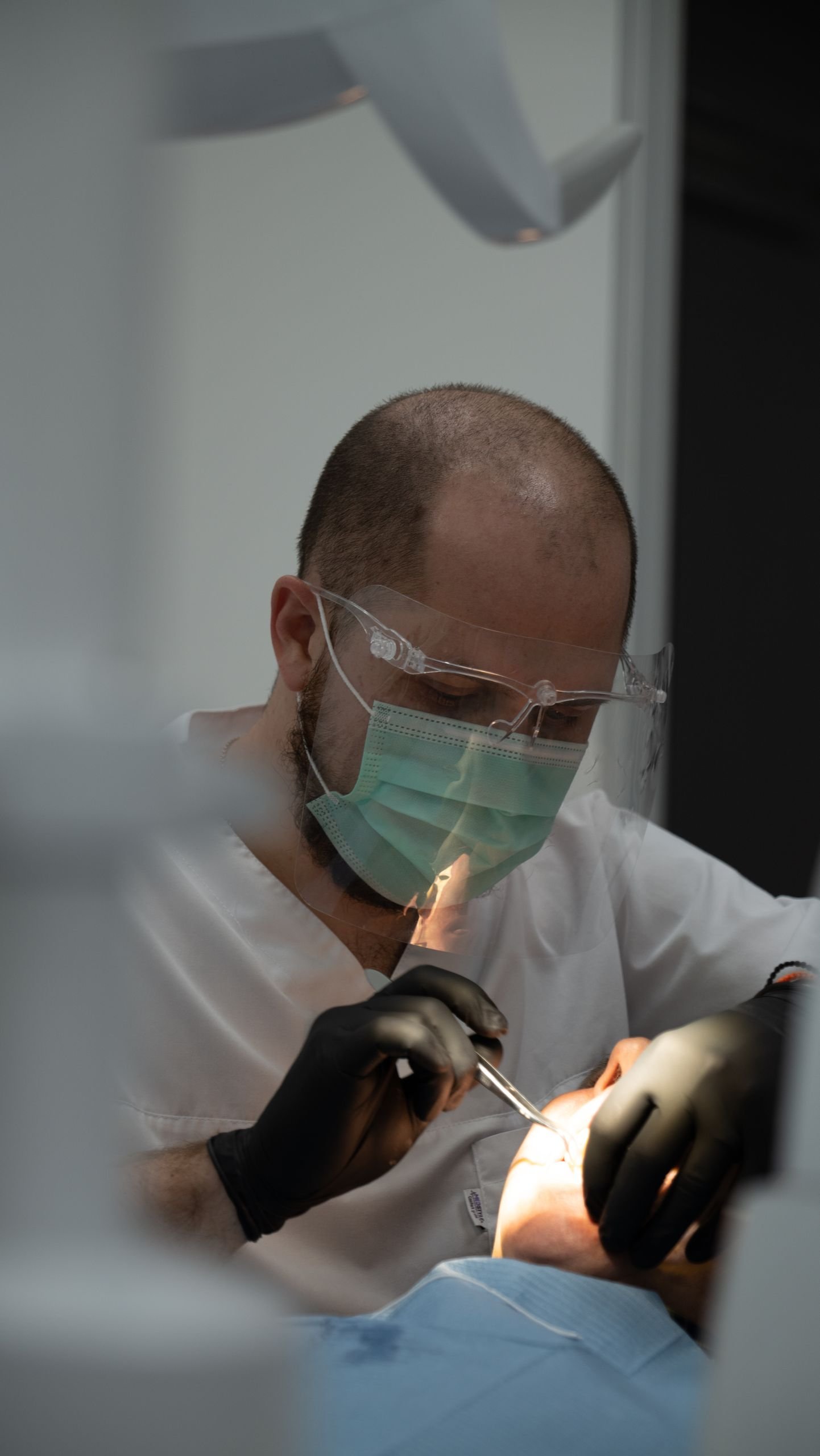 Dentist wearing protective gear treating a patient with precision.